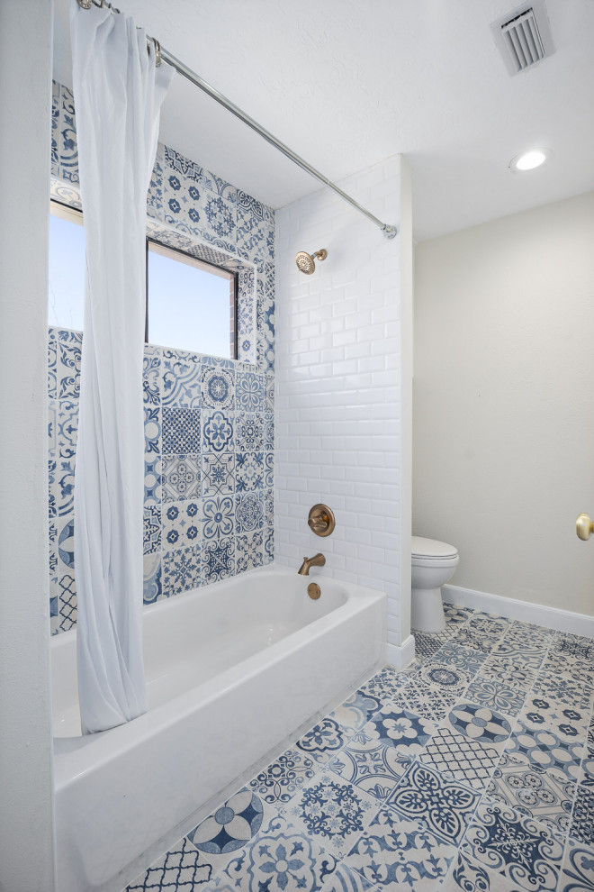 Photo of a mid-sized traditional kids bathroom in Houston with raised-panel cabinets, white cabinets, an alcove tub, a shower/bathtub combo, a two-piece toilet, blue tile, ceramic tile, beige walls, ceramic floors, an undermount sink, engineered quartz benchtops, blue floor, a shower curtain, white benchtops, a single vanity and a built-in vanity.