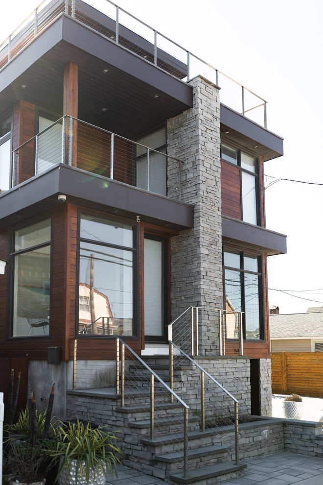 Стильный дизайн: трехэтажный, разноцветный частный загородный дом среднего размера в стиле модернизм с облицовкой из камня, плоской крышей, черной крышей и отделкой планкеном - последний тренд
