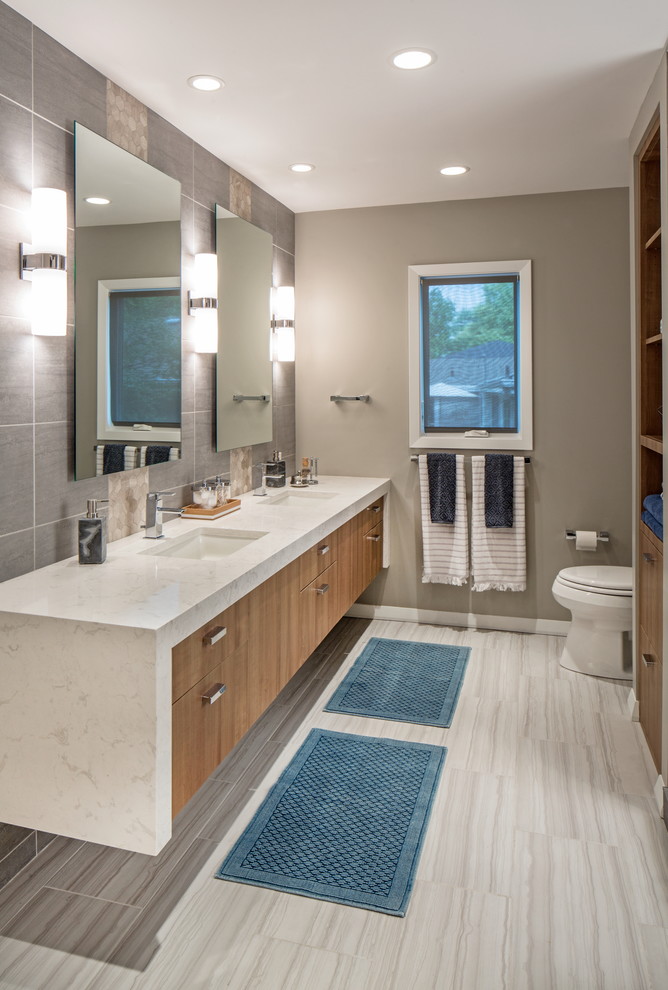 Design ideas for a mid-sized contemporary master bathroom in Omaha with flat-panel cabinets, medium wood cabinets, a curbless shower, a one-piece toilet, white tile, porcelain tile, grey walls, porcelain floors, an undermount sink and engineered quartz benchtops.