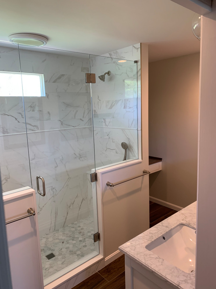 This is an example of a mid-sized traditional master bathroom in Cincinnati with shaker cabinets, white cabinets, a double shower, multi-coloured tile, porcelain tile, white walls, marble benchtops, brown floor, a hinged shower door, multi-coloured benchtops, a double vanity, a freestanding vanity and porcelain floors.