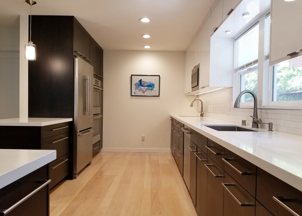 Inspiration for a mid-sized modern galley eat-in kitchen in San Francisco with an undermount sink, flat-panel cabinets, dark wood cabinets, quartz benchtops, white splashback, ceramic splashback, stainless steel appliances, light hardwood floors, with island, beige floor and white benchtop.
