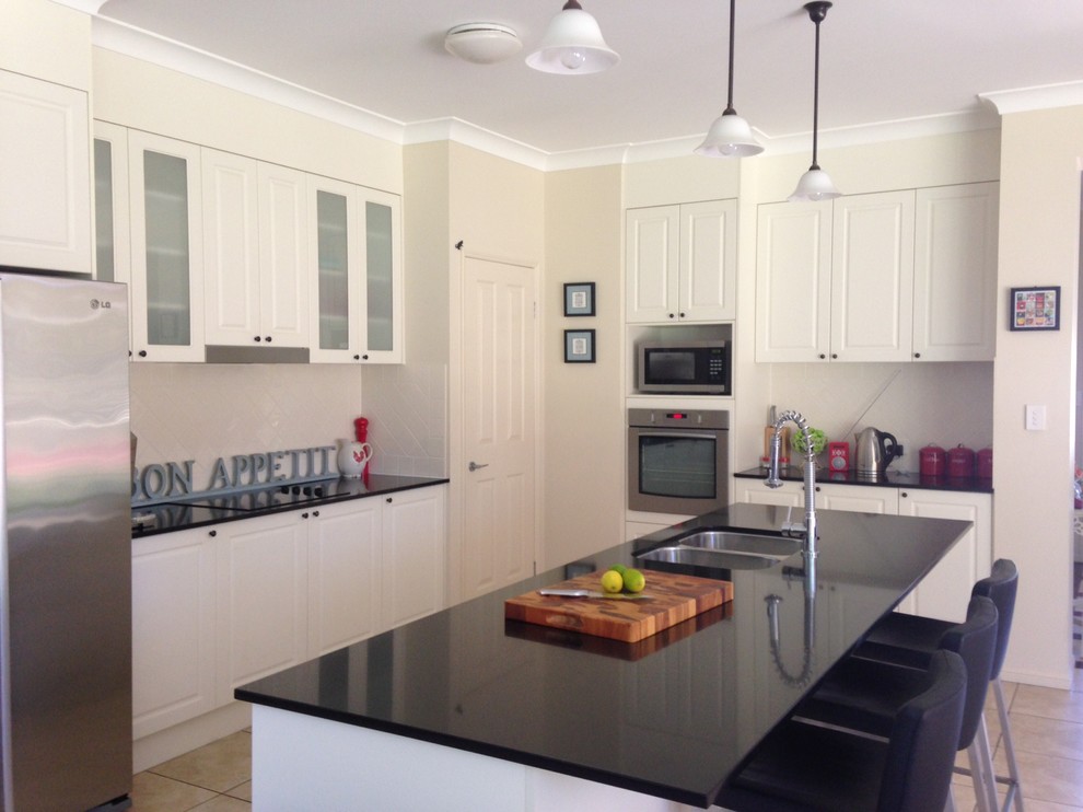 Inspiration for a large transitional l-shaped eat-in kitchen in Brisbane with an undermount sink, white cabinets, quartz benchtops, white splashback, ceramic splashback, stainless steel appliances, porcelain floors and with island.