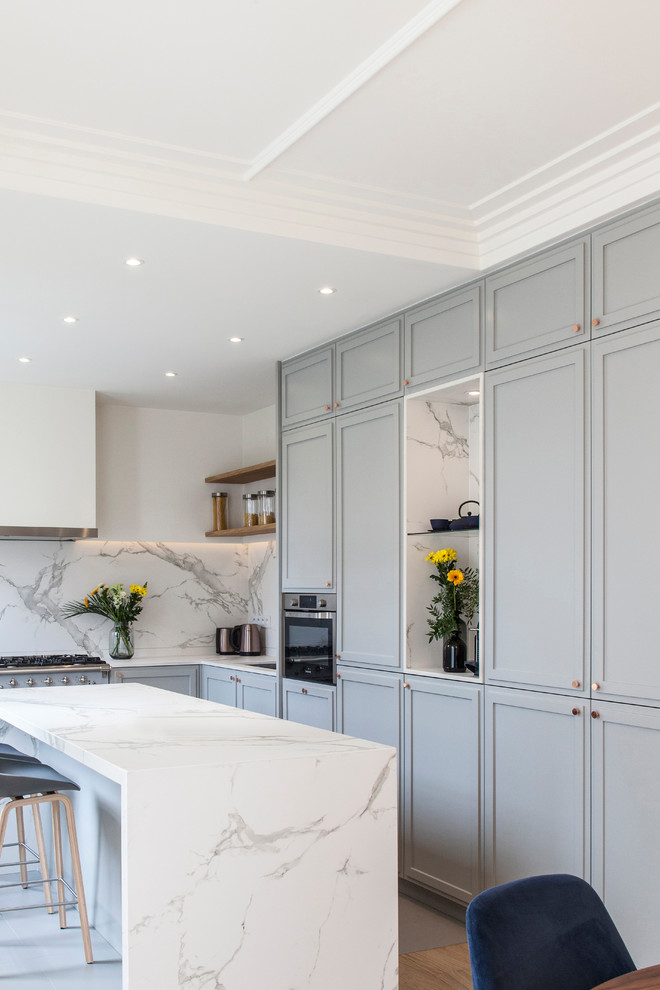 This is an example of a mid-sized contemporary l-shaped eat-in kitchen in Paris with an undermount sink, shaker cabinets, grey cabinets, marble benchtops, white splashback, marble splashback, panelled appliances, ceramic floors, with island, grey floor and white benchtop.
