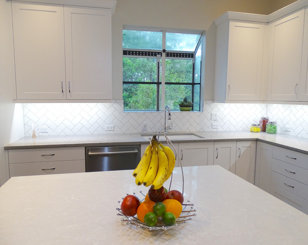 Large transitional galley ceramic tile eat-in kitchen photo in Austin with a drop-in sink, beaded inset cabinets, white cabinets, quartzite countertops, white backsplash, ceramic backsplash, stainless steel appliances and an island
