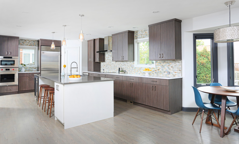 Photo of a large contemporary l-shaped kitchen in Chicago with an undermount sink, flat-panel cabinets, brown cabinets, quartz benchtops, beige splashback, stone tile splashback, stainless steel appliances, light hardwood floors and with island.