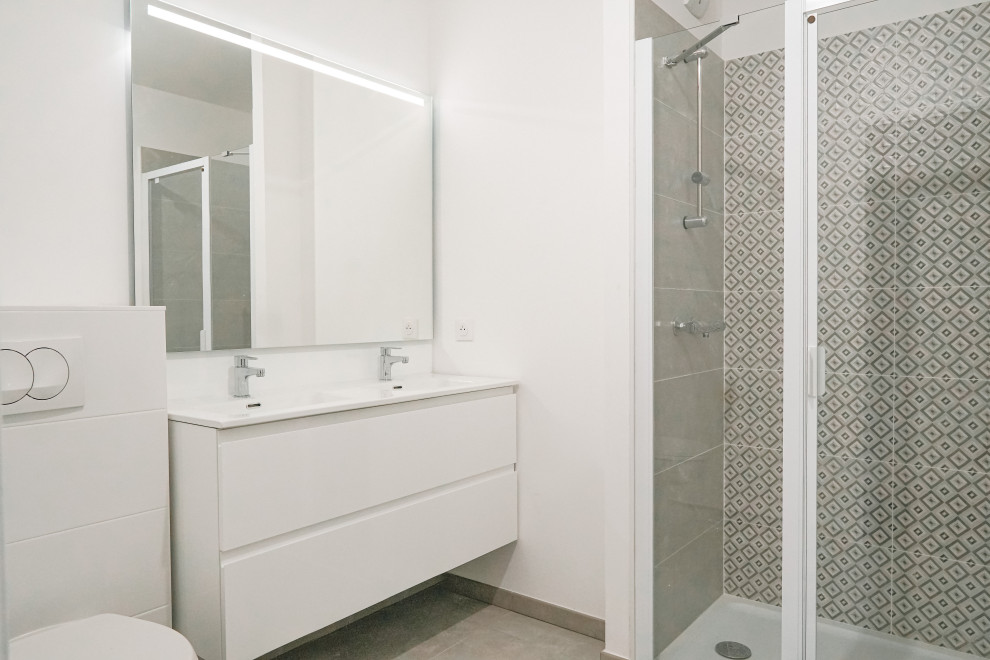 Aménagement d'une petite salle d'eau beige et blanche contemporaine avec des portes de placard blanches, WC suspendus, un mur blanc, un lavabo encastré, une cabine de douche à porte battante, un plan de toilette blanc, meuble double vasque et meuble-lavabo suspendu.