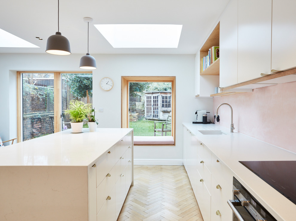 Foto på ett mellanstort funkis vit kök, med en integrerad diskho, släta luckor, vita skåp, bänkskiva i kvartsit, rosa stänkskydd, integrerade vitvaror, ljust trägolv och en halv köksö