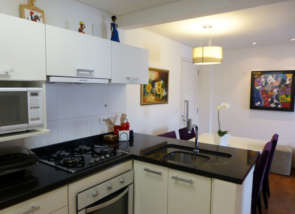 Small contemporary l-shaped eat-in kitchen in Other with a single-bowl sink, flat-panel cabinets, white cabinets, granite benchtops, white splashback, porcelain splashback, white appliances, porcelain floors and no island.
