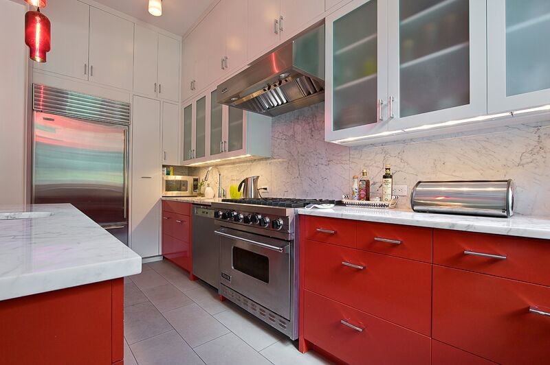 Design ideas for a mid-sized eclectic l-shaped eat-in kitchen in New York with an undermount sink, flat-panel cabinets, red cabinets, marble benchtops, white splashback, stone slab splashback, stainless steel appliances, ceramic floors and with island.