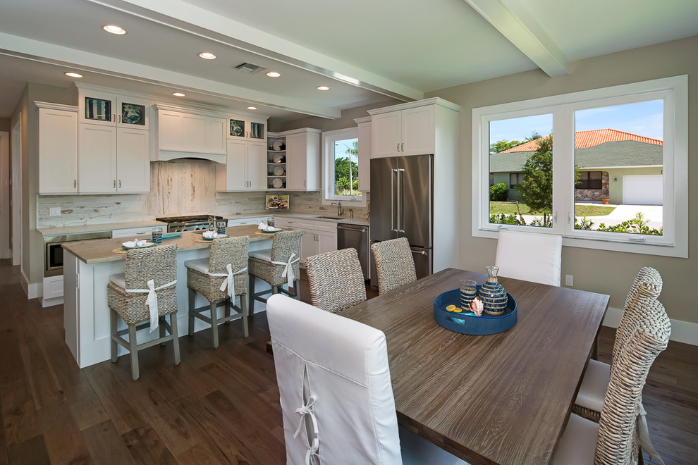 Design ideas for a large beach style eat-in kitchen in Miami with an undermount sink, shaker cabinets, white cabinets, marble benchtops, white splashback, ceramic splashback, stainless steel appliances, medium hardwood floors and with island.