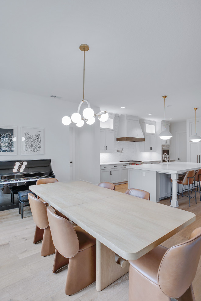 Idee per una grande sala da pranzo aperta verso la cucina moderna con pareti bianche, parquet chiaro e pavimento beige