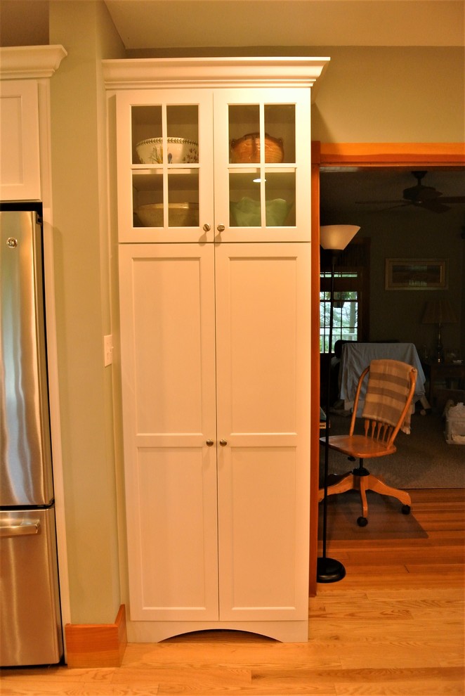 Example of a transitional light wood floor kitchen design in Boston with an undermount sink, shaker cabinets, white cabinets, quartzite countertops, white backsplash, subway tile backsplash, stainless steel appliances and an island