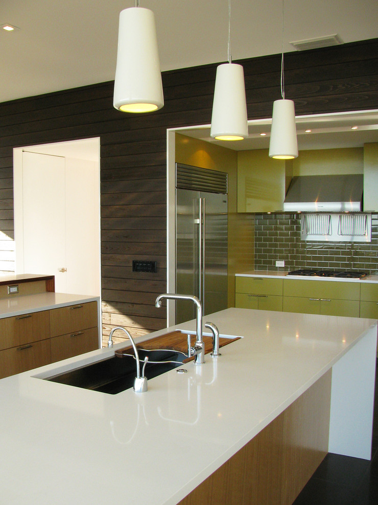 This is an example of a mid-sized modern open plan kitchen in Austin with a double-bowl sink, light wood cabinets, green splashback, ceramic splashback, stainless steel appliances, flat-panel cabinets, ceramic floors, multiple islands and brown floor.