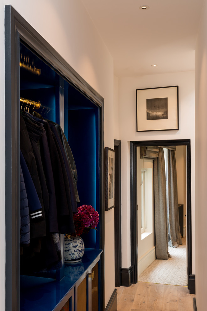 Photo of a small eclectic gender-neutral dressing room in London with open cabinets, blue cabinets, medium hardwood floors and brown floor.
