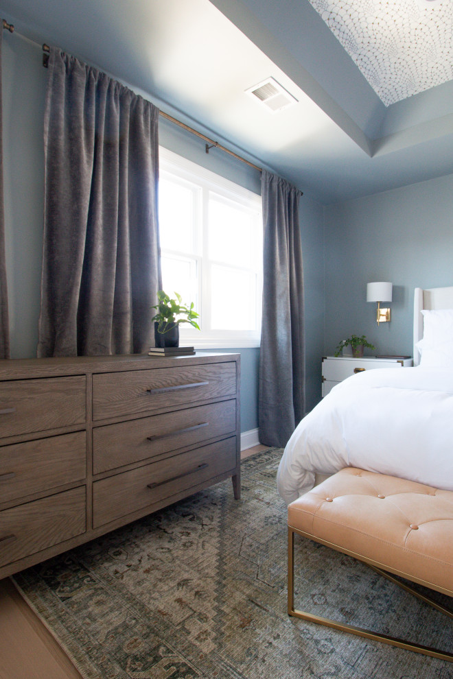 Cette image montre une chambre minimaliste de taille moyenne avec un mur bleu, parquet clair, aucune cheminée et un sol marron.