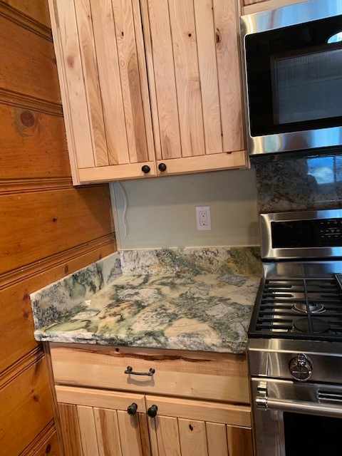 Mid-sized mountain style medium tone wood floor and brown floor open concept kitchen photo with an undermount sink, flat-panel cabinets, light wood cabinets, granite countertops, gray backsplash, stone slab backsplash, stainless steel appliances and gray countertops