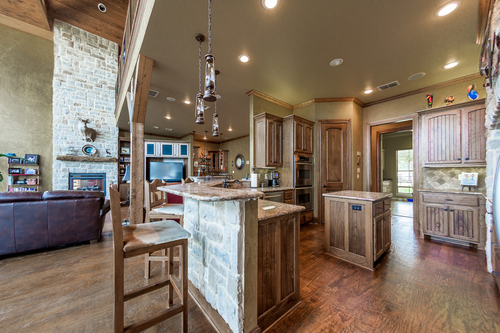 Photo of a large country u-shaped open plan kitchen in Austin with beaded inset cabinets, distressed cabinets, granite benchtops, brown splashback, stone tile splashback, stainless steel appliances, dark hardwood floors and with island.