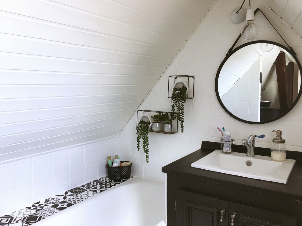 Photo of a small midcentury 3/4 bathroom in Strasbourg with beige cabinets, an undermount tub, white tile, ceramic tile, white walls, vinyl floors, an undermount sink, laminate benchtops, beige floor and black benchtops.
