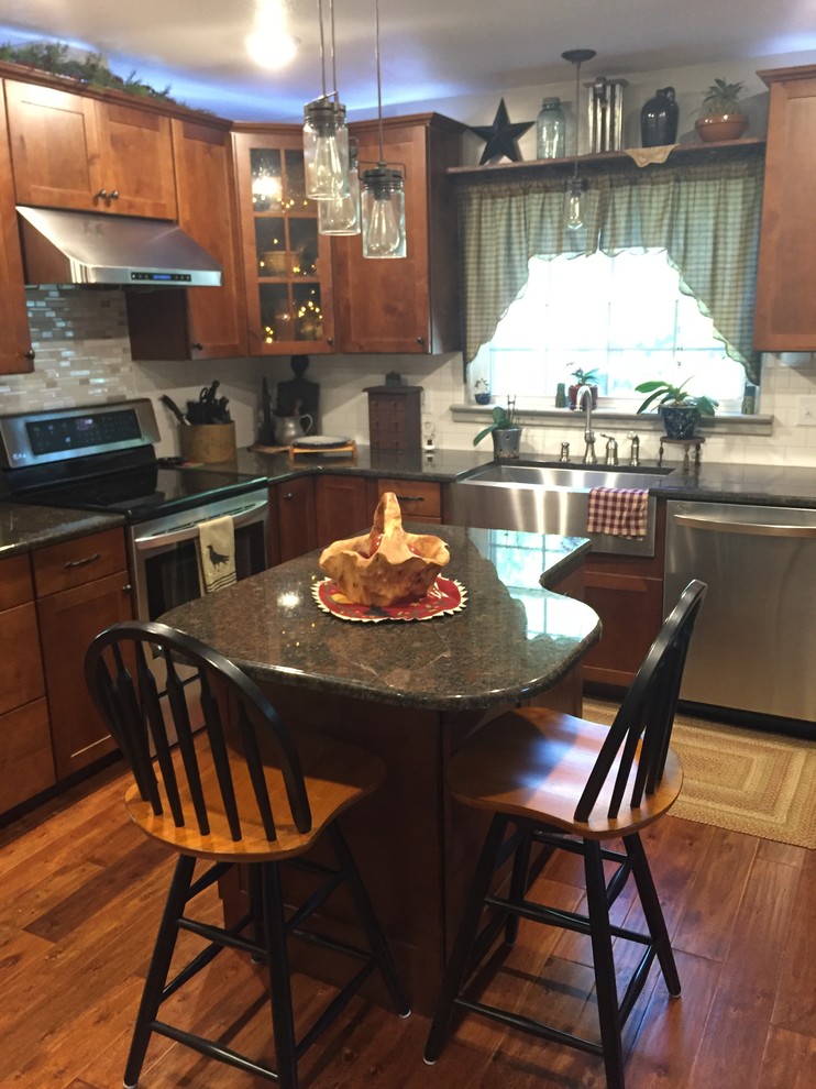 Enclosed kitchen - mid-sized transitional u-shaped enclosed kitchen idea with a farmhouse sink, shaker cabinets, medium tone wood cabinets, granite countertops, white backsplash, stainless steel appliances and an island