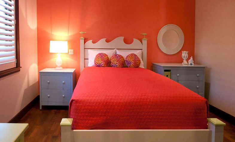 This is an example of a mid-sized tropical guest bedroom in Portland with red walls, dark hardwood floors, no fireplace and brown floor.