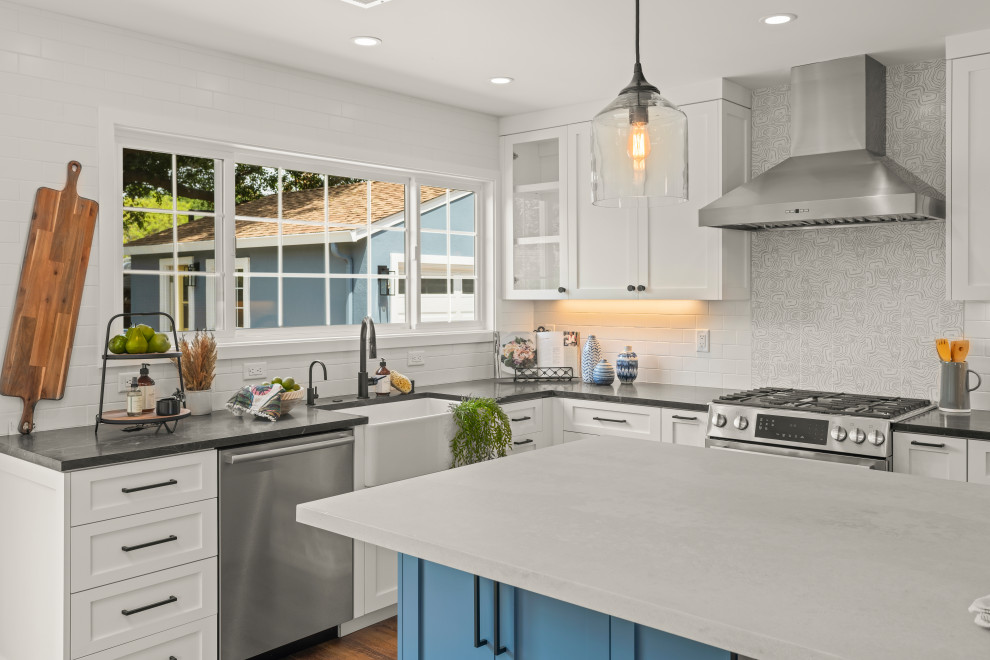 Inspiration for a large contemporary l-shaped eat-in kitchen in San Francisco with a farmhouse sink, shaker cabinets, white cabinets, soapstone benchtops, white splashback, porcelain splashback, stainless steel appliances, vinyl floors, with island, brown floor and black benchtop.
