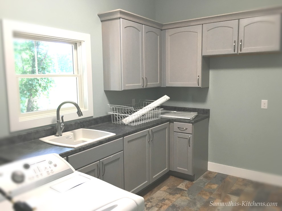 Large transitional l-shaped porcelain tile home design photo with a drop-in sink, recessed-panel cabinets, gray cabinets, laminate countertops, blue walls and a side-by-side washer/dryer