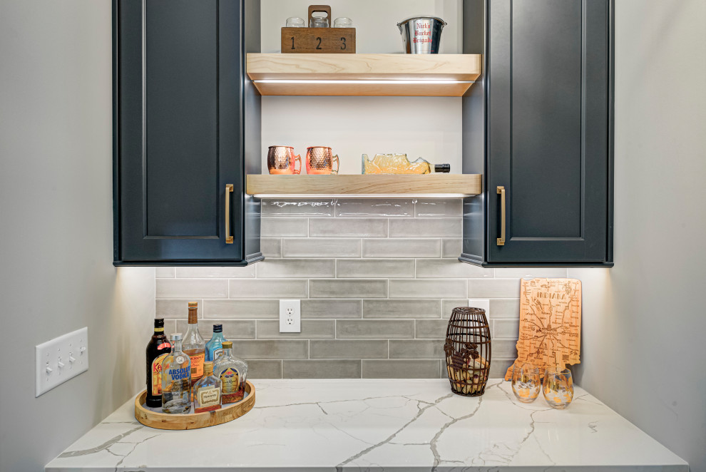 Inspiration for a mid-sized transitional single-wall home bar in Indianapolis with shaker cabinets, black cabinets, granite benchtops, subway tile splashback, white benchtop and grey splashback.