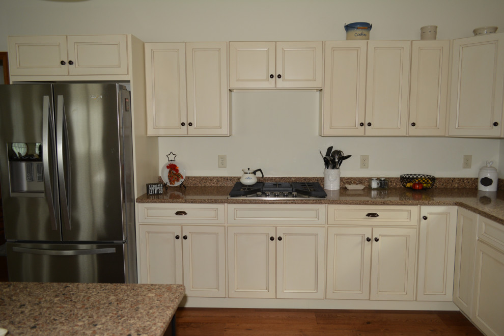 Klassisk inredning av ett litet brun brunt kök, med en undermonterad diskho, släta luckor, beige skåp, bänkskiva i kvarts, rostfria vitvaror, mellanmörkt trägolv, en köksö och brunt golv