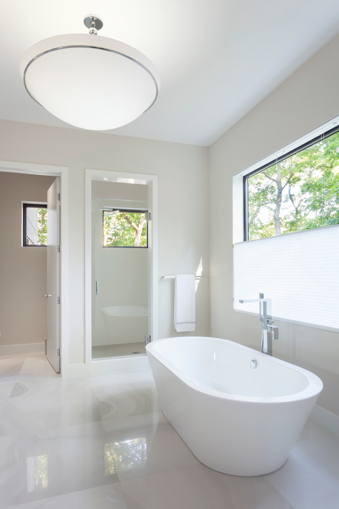 This is an example of a large contemporary master bathroom in Miami with flat-panel cabinets, white cabinets, a freestanding tub, an alcove shower, beige walls, marble floors, an undermount sink, solid surface benchtops, white floor, a hinged shower door and white benchtops.