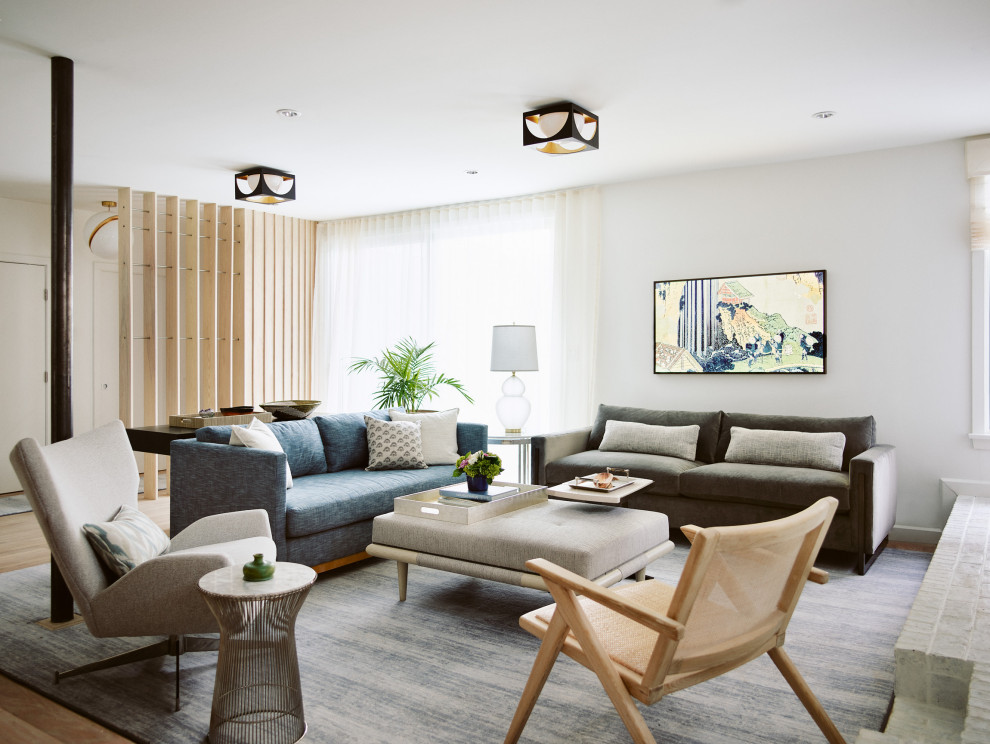 Стильный дизайн: изолированная гостиная комната среднего размера в стиле модернизм с белыми стенами, паркетным полом среднего тона, стандартным камином и фасадом камина из металла без телевизора - последний тренд