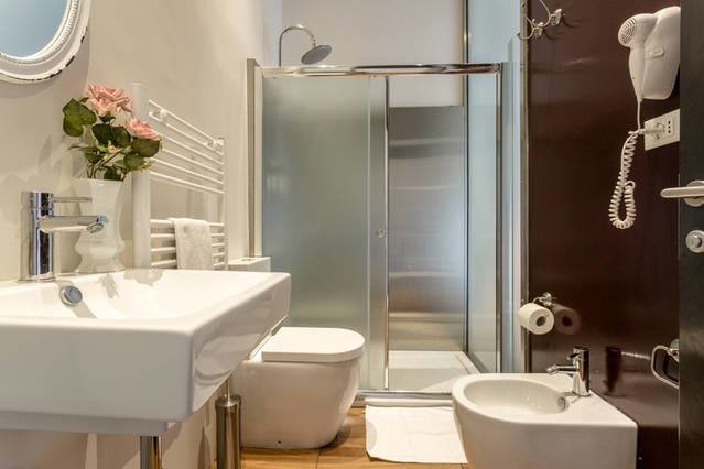 This is an example of a small traditional 3/4 bathroom in Rome with a curbless shower, a two-piece toilet, red tile, mirror tile, light hardwood floors, a vessel sink, open cabinets, red cabinets, red walls, solid surface benchtops and a sliding shower screen.