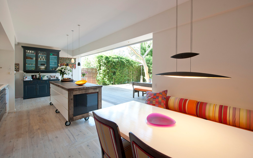 This is an example of a mid-sized contemporary l-shaped eat-in kitchen in Sydney with flat-panel cabinets, white cabinets, wood benchtops, light hardwood floors and with island.