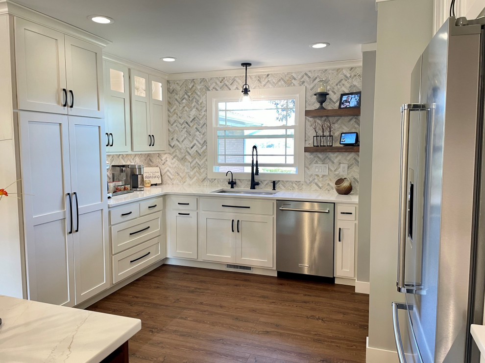 Bild på ett stort vintage vit vitt kök, med en undermonterad diskho, släta luckor, vita skåp, bänkskiva i kvarts, flerfärgad stänkskydd, stänkskydd i stenkakel, rostfria vitvaror, mellanmörkt trägolv, en köksö och brunt golv