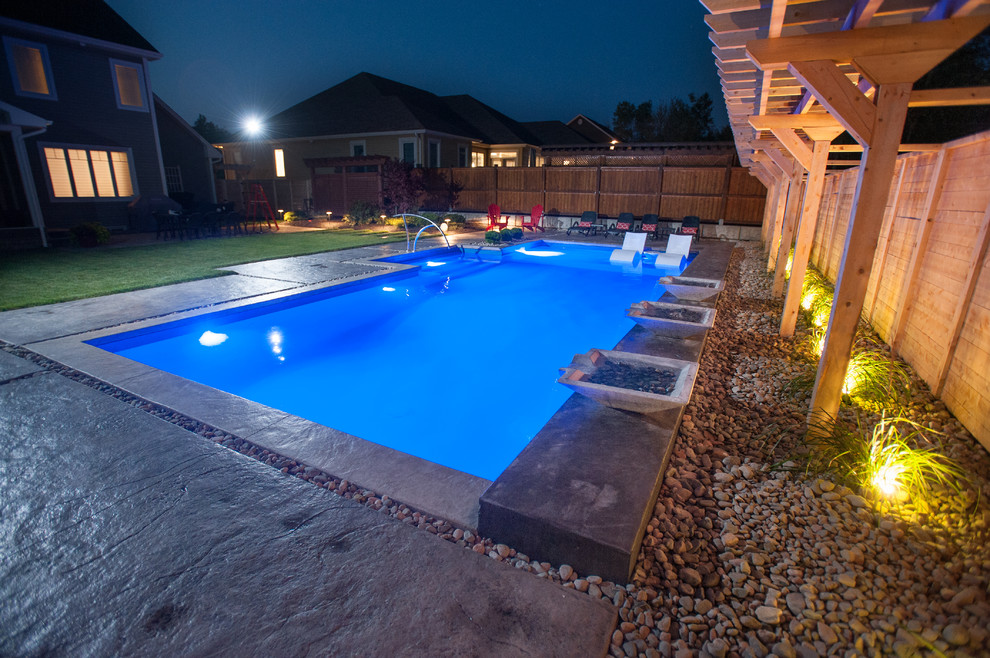 Large contemporary backyard custom-shaped lap pool in Other with a water feature and stamped concrete.
