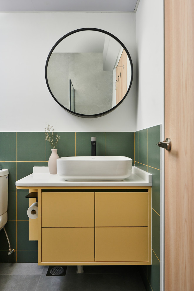 This is an example of a contemporary bathroom in Singapore with flat-panel cabinets, yellow cabinets, green tile, white walls, a vessel sink, grey floor, white benchtops, a single vanity and a floating vanity.