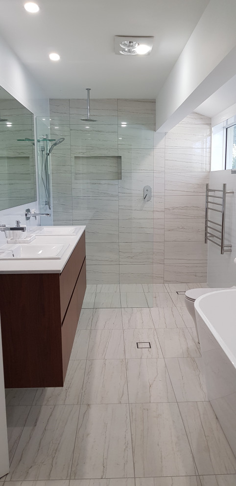 This is an example of a mid-sized modern master bathroom in Brisbane with a freestanding tub, an open shower, a one-piece toilet, white tile, porcelain tile, porcelain floors, a drop-in sink, engineered quartz benchtops, beige floor and white benchtops.