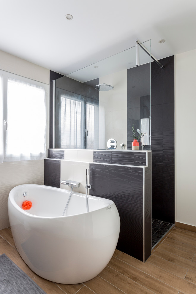 This is an example of a mid-sized contemporary master bathroom in Bordeaux with a freestanding tub, a curbless shower, beige walls, ceramic floors, a vessel sink and black and white tile.