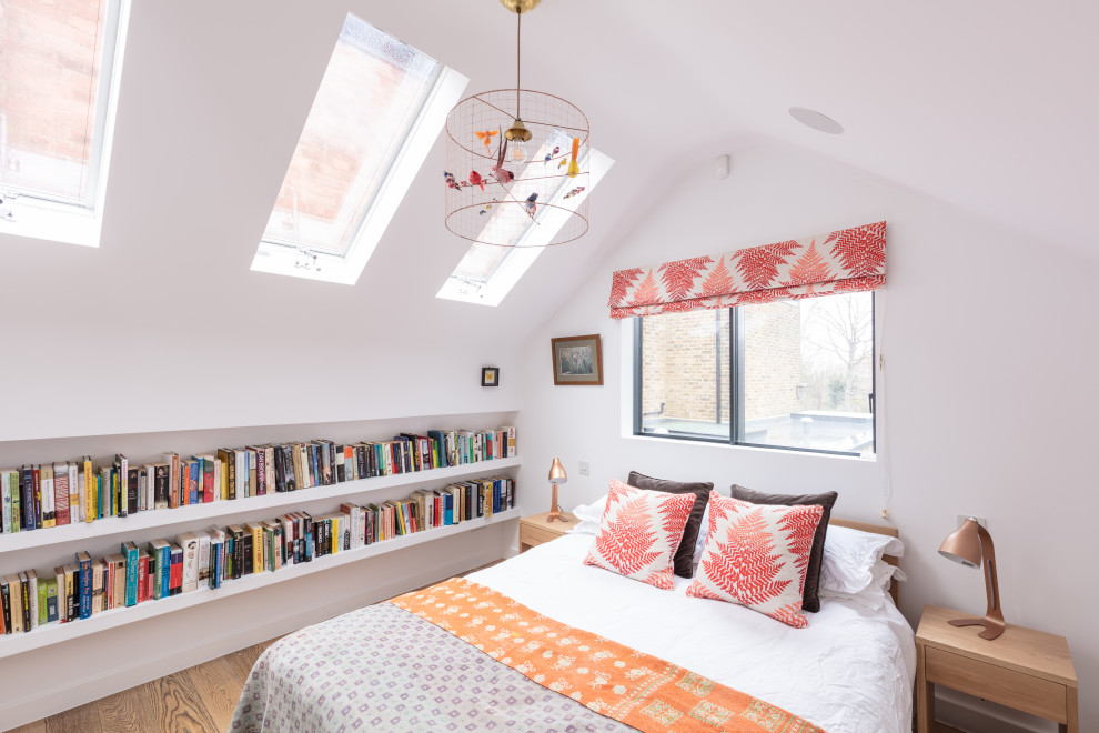 This is an example of a mid-sized contemporary guest bedroom in London with white walls and light hardwood floors.