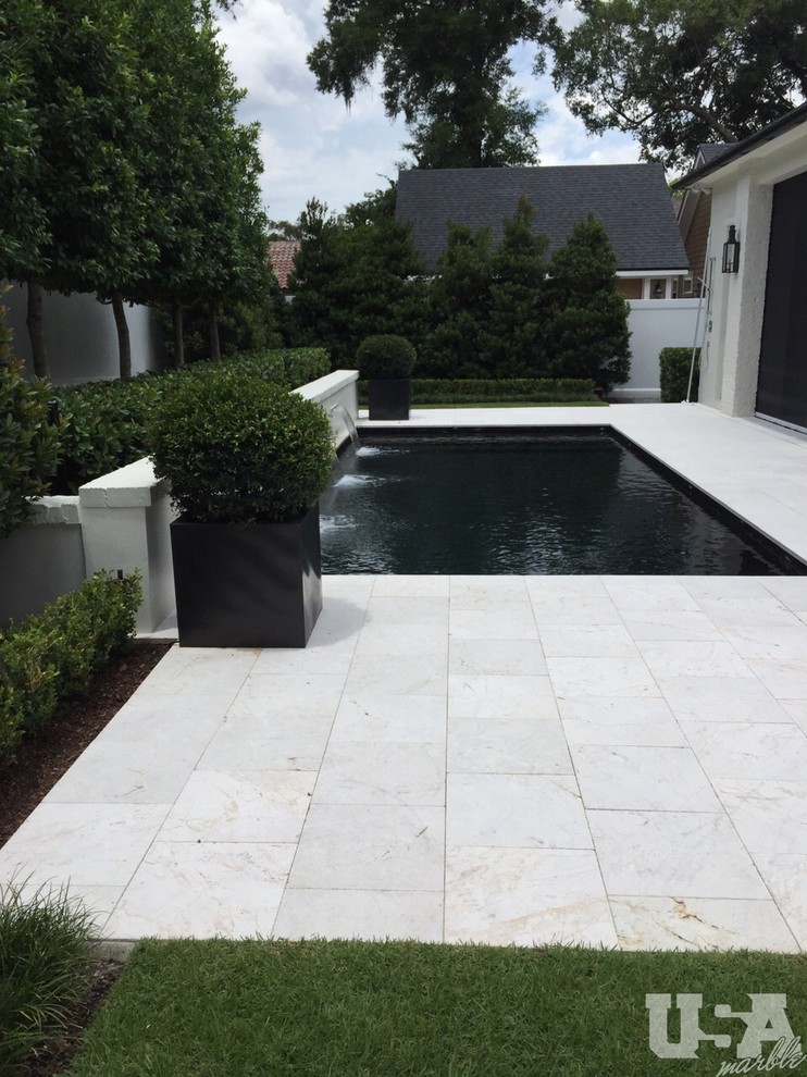 Inspiration for a mid-sized modern aboveground pool in Orlando with natural stone pavers.