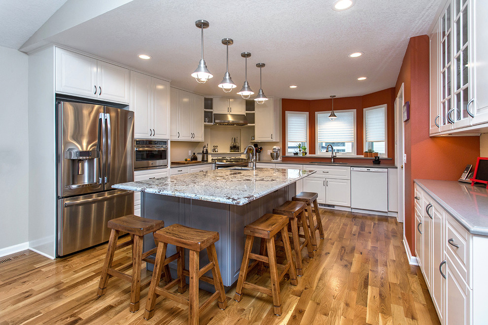 Mid-sized transitional u-shaped medium tone wood floor open concept kitchen photo with an undermount sink, raised-panel cabinets, white cabinets, quartz countertops, gray backsplash, porcelain backsplash, stainless steel appliances and an island