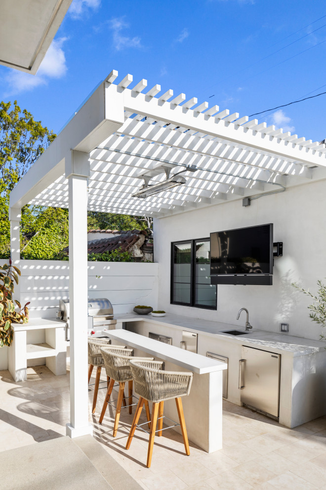 Large mediterranean courtyard patio in Los Angeles with an outdoor kitchen, tiled flooring and a pergola.