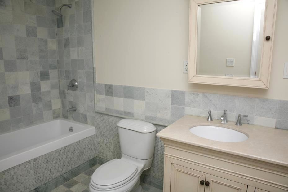 Mid-sized contemporary master bathroom in New York with an undermount sink, beaded inset cabinets, beige cabinets, granite benchtops, an alcove tub, a shower/bathtub combo, a two-piece toilet, green tile, mosaic tile, beige walls and marble floors.
