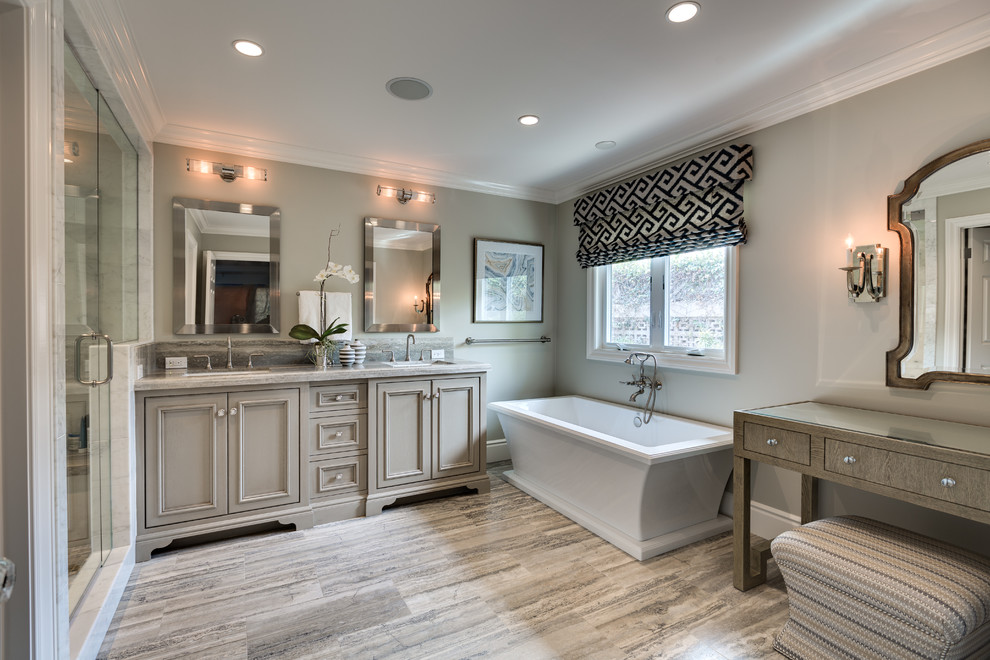 Design ideas for a mid-sized transitional master bathroom in Orange County with recessed-panel cabinets, grey cabinets, a freestanding tub, an alcove shower, gray tile, white walls, light hardwood floors, an undermount sink, marble, marble benchtops, beige floor and a hinged shower door.