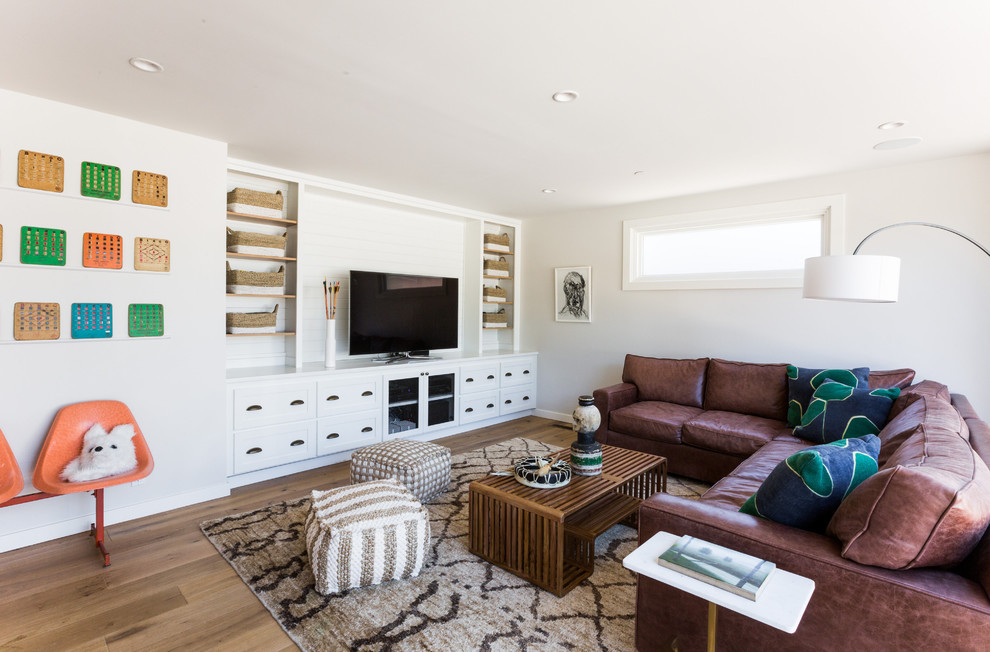 Photo of a transitional open concept living room in Sacramento with white walls, medium hardwood floors, a built-in media wall and brown floor.
