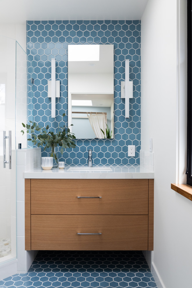 This is an example of a small midcentury family bathroom in Other with flat-panel cabinets, medium wood cabinets, a corner shower, a one-piece toilet, blue tiles, ceramic tiles, white walls, ceramic flooring, a submerged sink, engineered stone worktops, blue floors, a hinged door, white worktops, a wall niche, a single sink and a floating vanity unit.