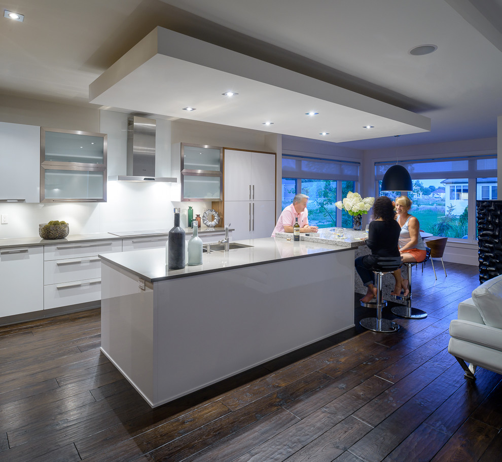 Contemporary galley open plan kitchen in Ottawa with flat-panel cabinets, white cabinets, white splashback, stainless steel appliances and an undermount sink.