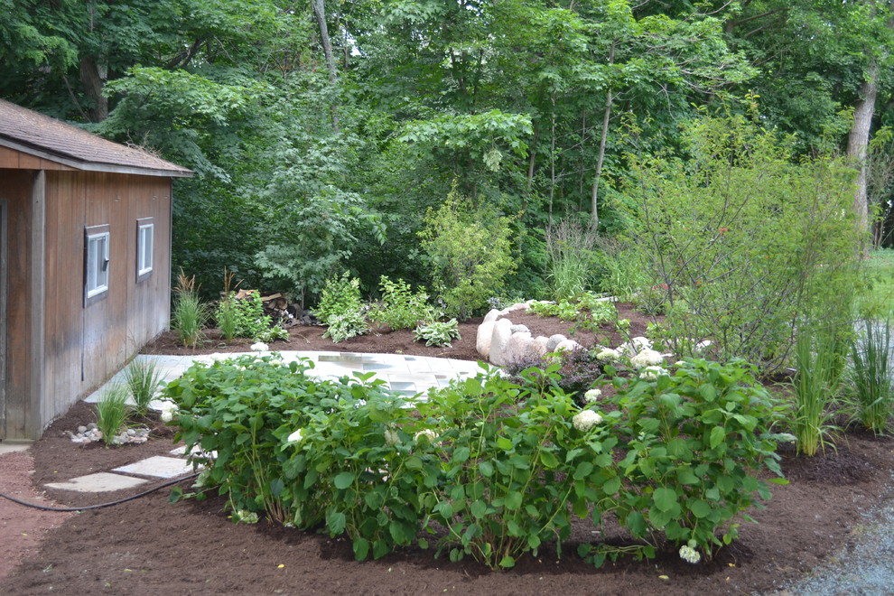 Inspiration for a mid-sized rustic backyard stone landscaping in Milwaukee.