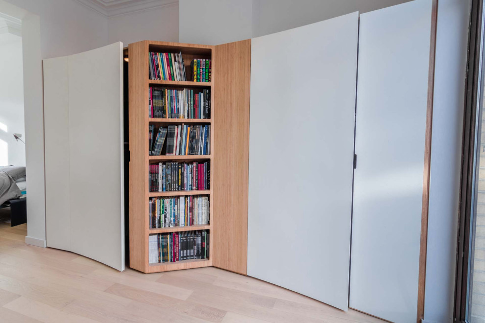 Photo of an expansive contemporary gender-neutral storage and wardrobe in Paris with beaded inset cabinets, white cabinets, light hardwood floors, beige floor and recessed.
