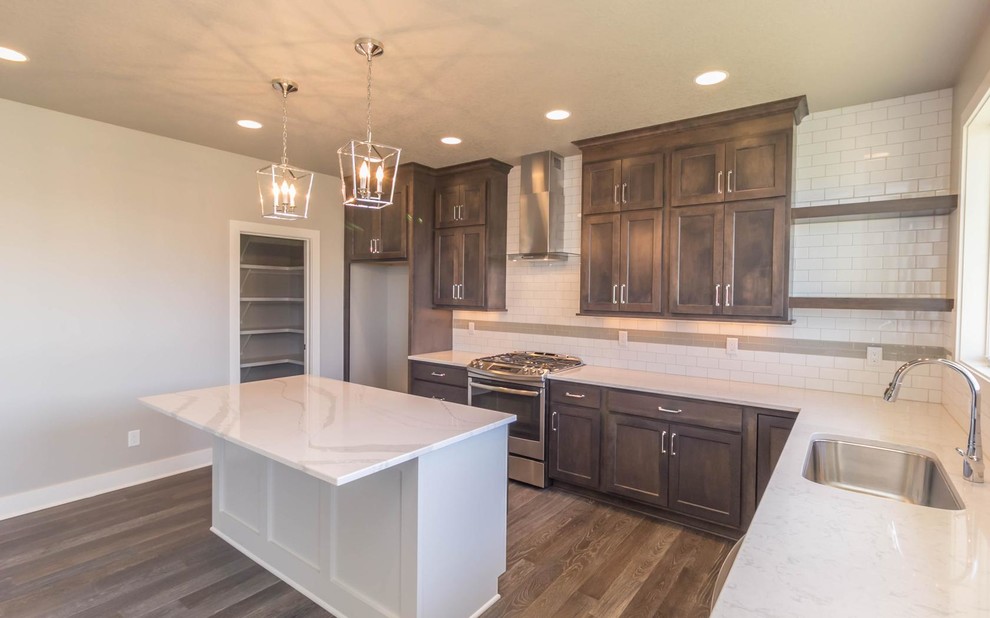 Example of a mid-sized transitional l-shaped medium tone wood floor open concept kitchen design with an undermount sink, shaker cabinets, dark wood cabinets, marble countertops, white backsplash, subway tile backsplash, stainless steel appliances and an island