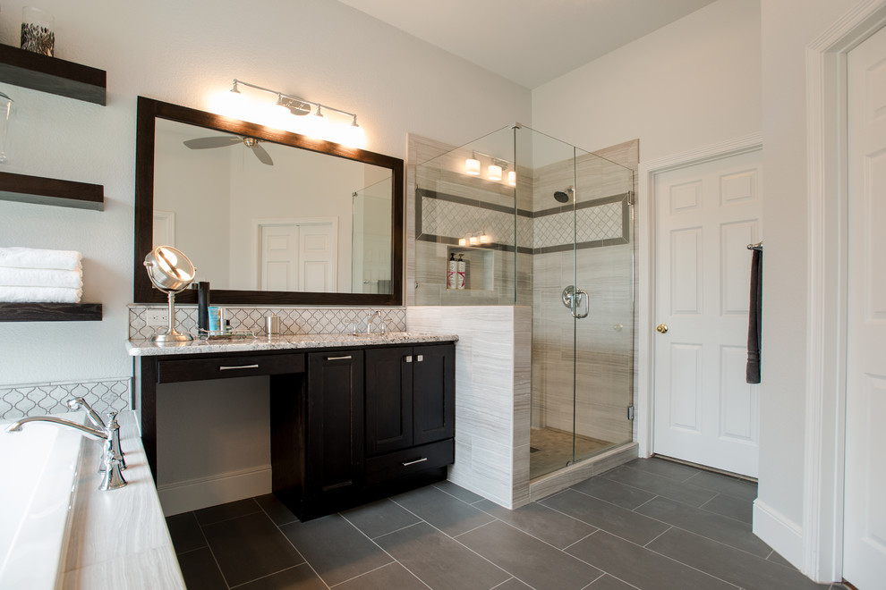Photo of a mid-sized transitional master bathroom in Dallas with shaker cabinets, dark wood cabinets, a corner tub, a corner shower, a one-piece toilet, gray tile, mosaic tile, grey walls, porcelain floors, a drop-in sink and granite benchtops.